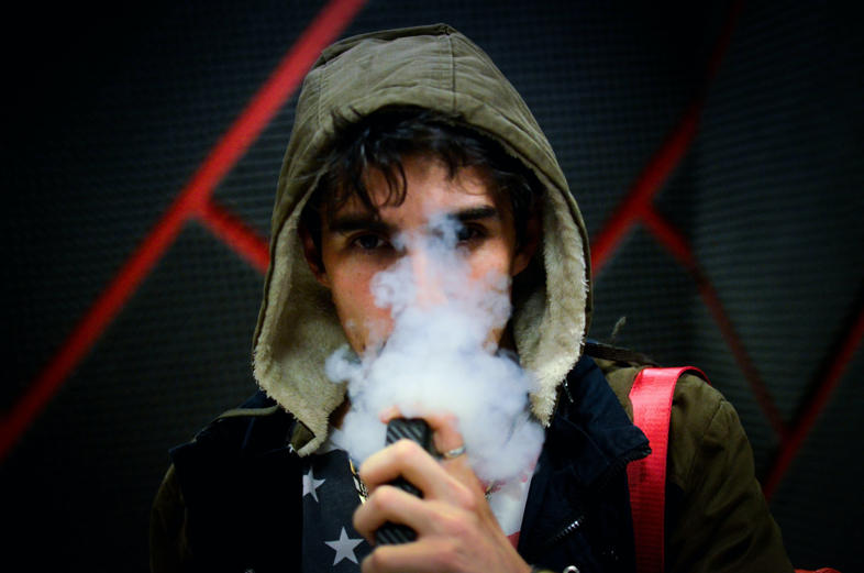 Un garçon fume une cigarette électronique