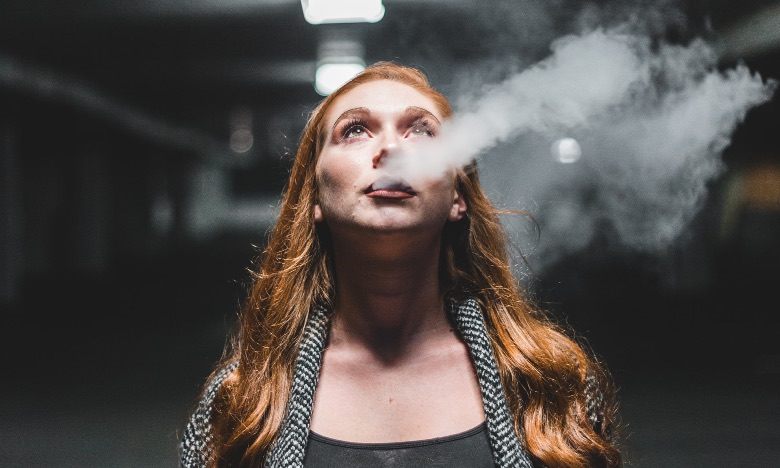 Femme vapotante avec une cigarette électronique