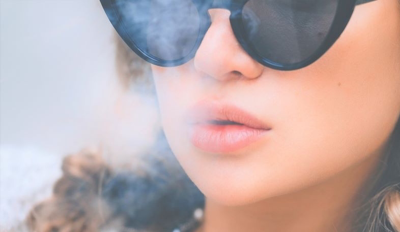 Fille vapotant avec une e-cigarette qui ne fait pas beaucoup de vapeur.