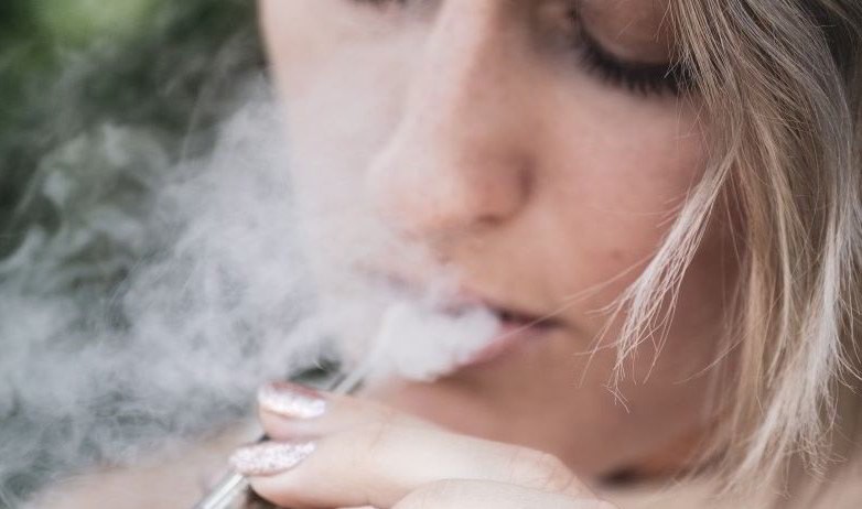 Fille inhalant la vapeur de la cigarette électronique