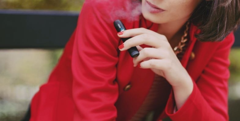 Femme fumant avec une cigarette électronique compacte