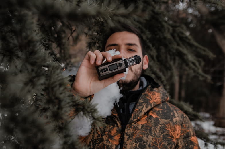 Garçon fumant avec une cigarette électronique moderne