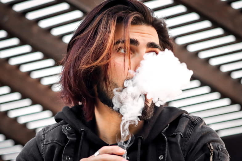 Un garçon fume une e-cig avec un liquide préparé à la maison